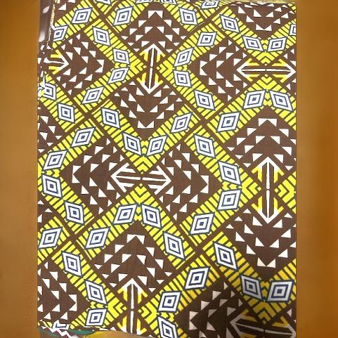 African Print Geometric Brown/Yellow Headwrap with bold tribal diamond patterns in yellow, brown, white, and blue. Made from premium cotton fabric.