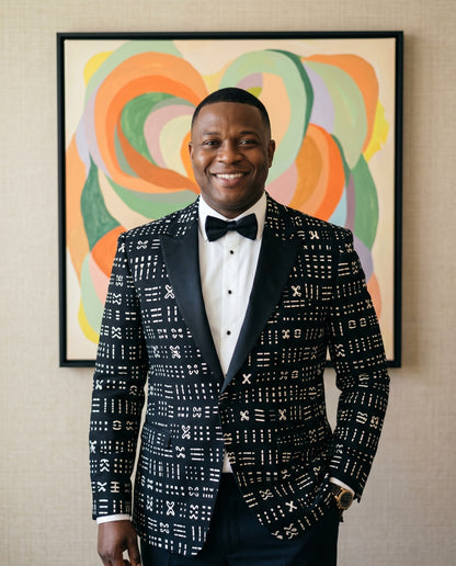 Man in a patterned suit standing in front of abstract wall art