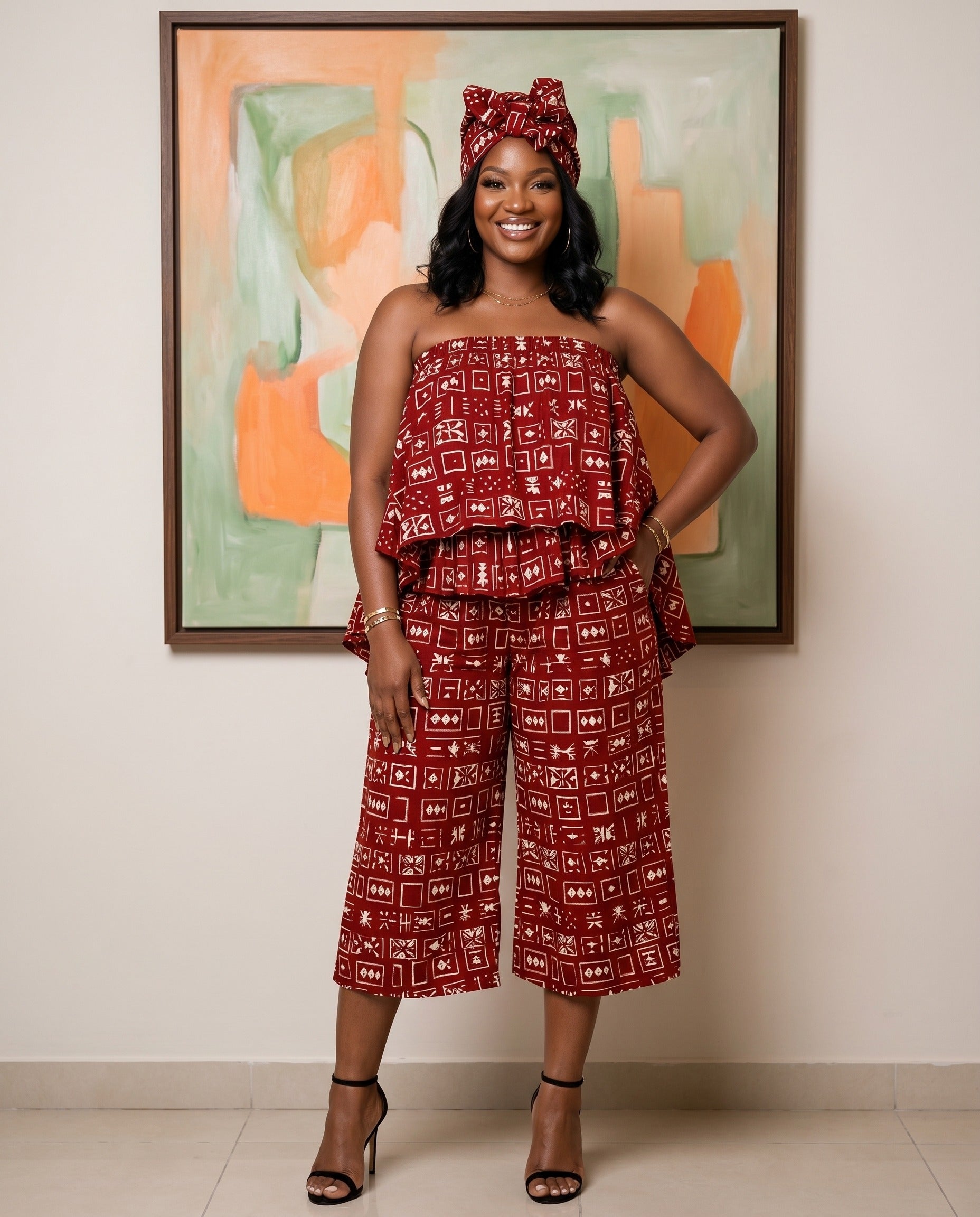 Woman in a red patterned outfit standing in front of a colorful abstract painting.