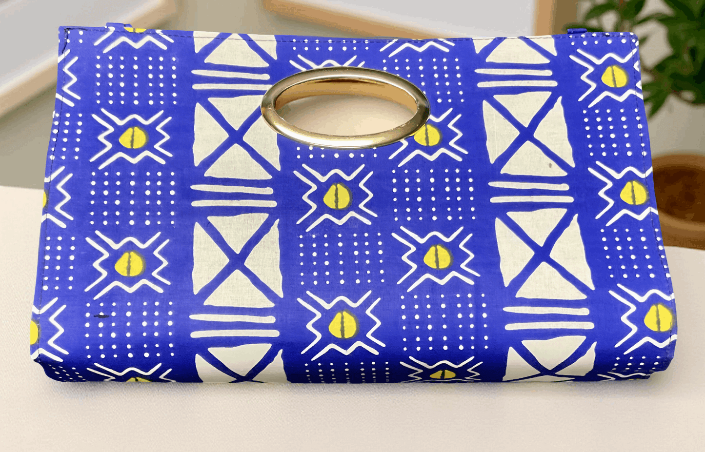 Blue and white patterned pouch with a gold ring on a light background