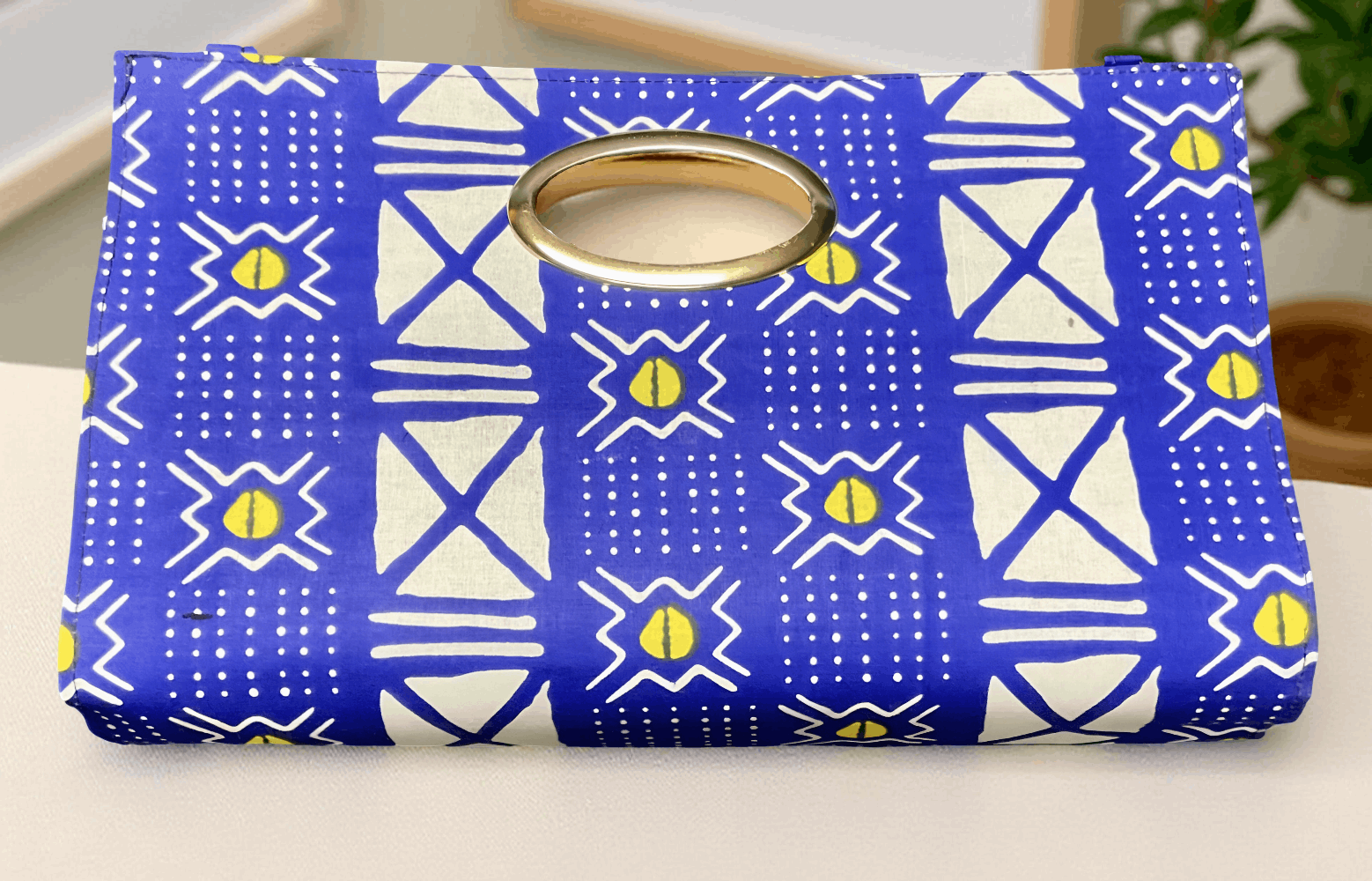 Blue and white patterned pouch with a gold ring on a light background