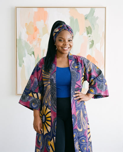 Woman wearing a colorful patterned coat in front of abstract art