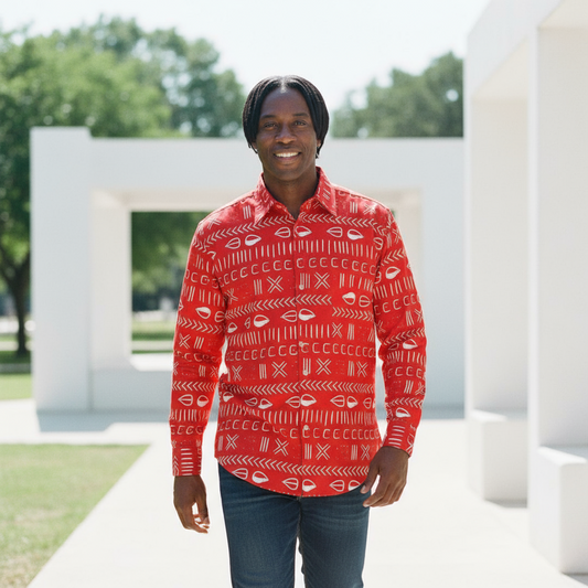 Person wearing a red patterned shirt standing outdoors with greenery in the background